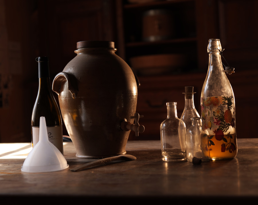 Vinaigrier en grès, bouteilles et entonnoir pour préparer une production de vinaigre