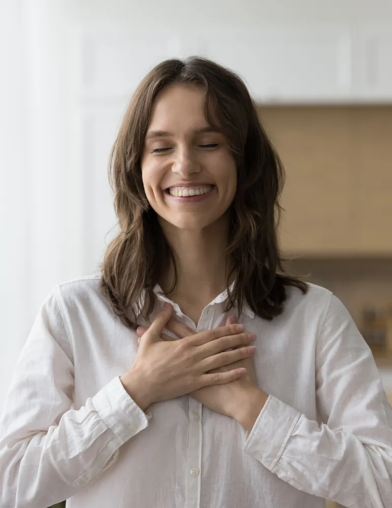 Une femme sourit, les mains posées sur le cœur
