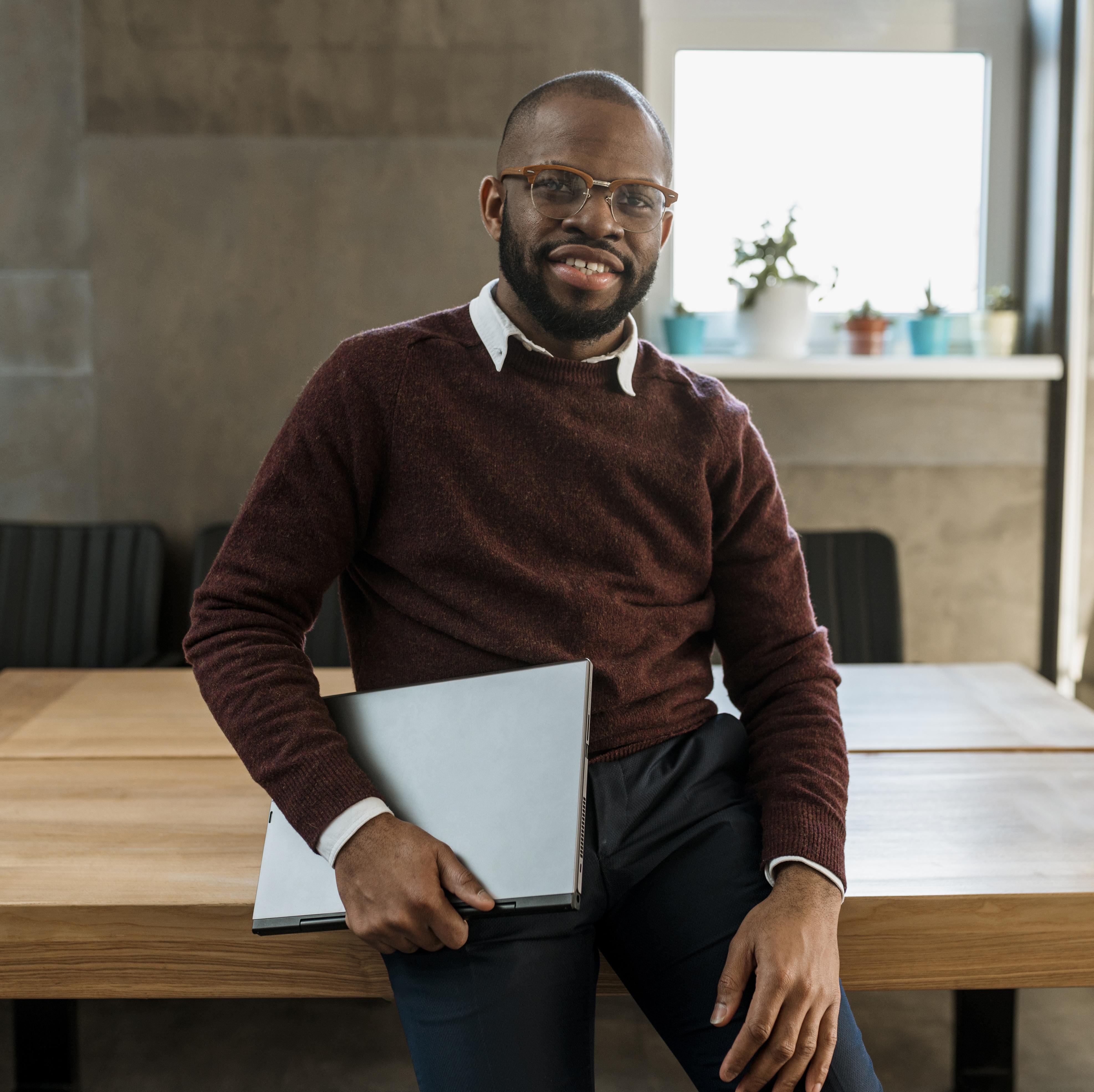 homme-souriant-portant-un-ordinateur-portable