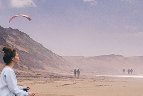 Femme en méditation sur une plage pour libérer ces mémoires transgénérationnelles et ses ancêtres afin de pouvoir prendre son envol dans sa vie.